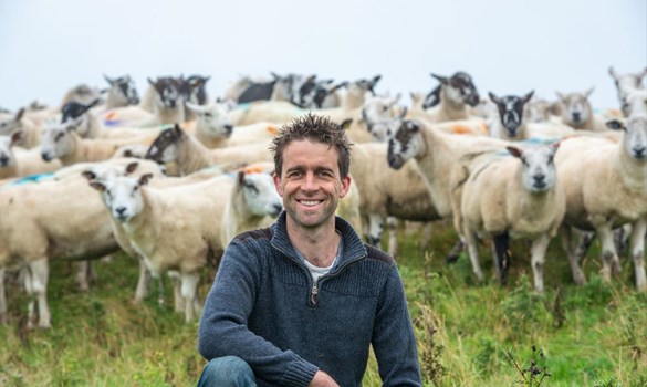 Steven Lawson sat in a field of sheep